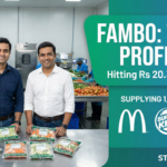 Co-founders of Fambo, Akshay Tripathi and Sudarshan Satle, at their Noida processing facility holding semi-processed vegetable packs. Logos of clients McDonald's, Burger King, and Barbeque Nation are visible on a green StartupFeed background.