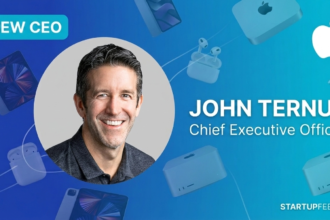 Apple new CEO announcement featured image for StartupFeed.in, showing John Ternus (SVP Hardware) as the successor to Tim Cook, surrounded by iconic Apple hardware like iPad, Mac Studio, and AirPods on a premium blue gradient.